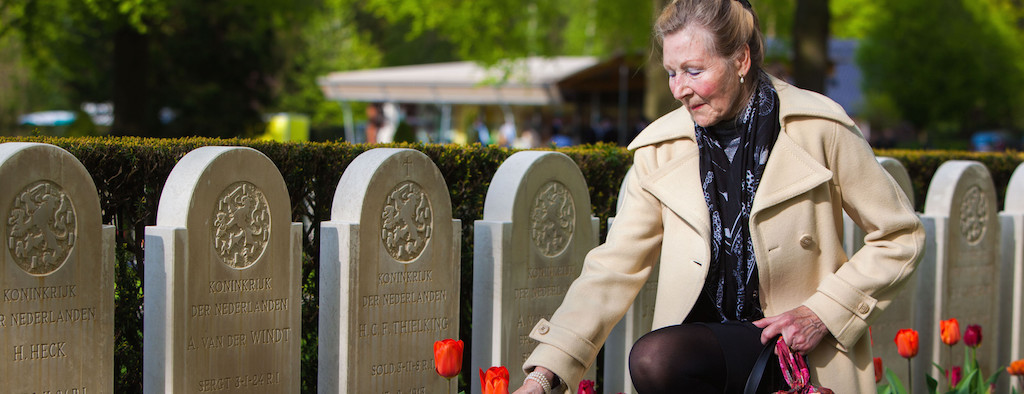 vrouw legt bloemen bij een graf